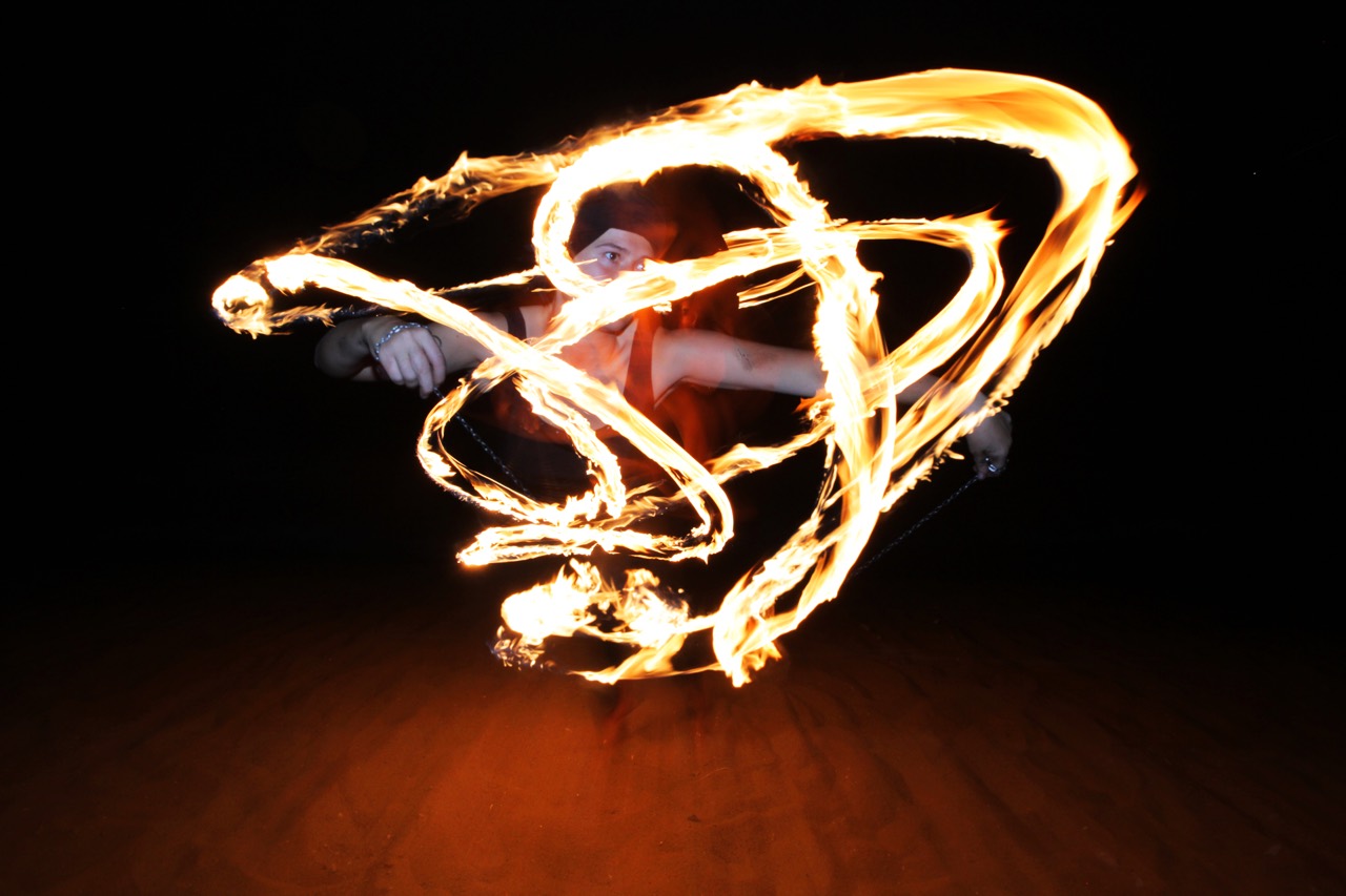 Female fire dancer surrounded by tracers